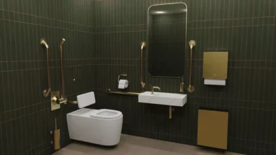 An inclusive, disability-friendly public restroom with green and gold tiles, a toilet, a sink and rails
