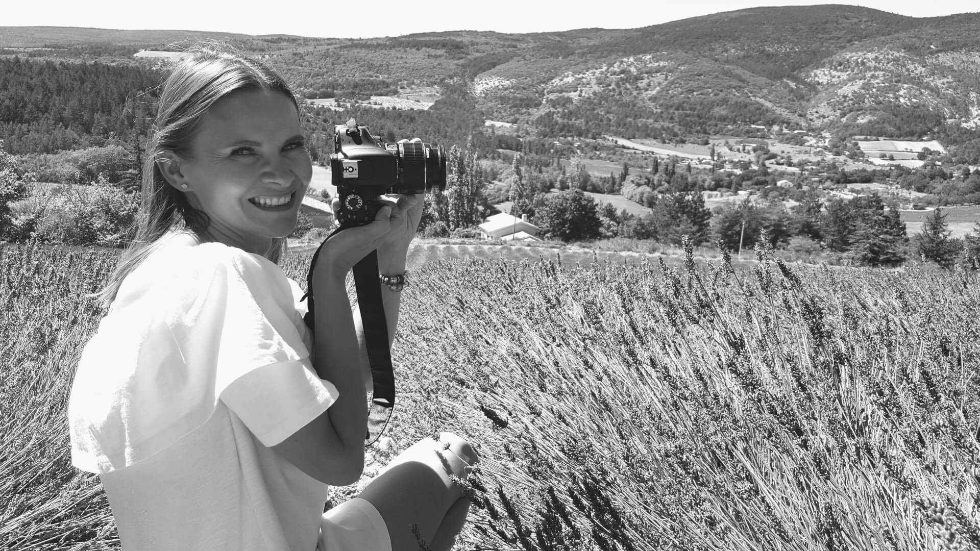 Black and white image of Diana Sarna, co-owner of Polish architectural firm Sarna Architekci, holding a camera in a field 